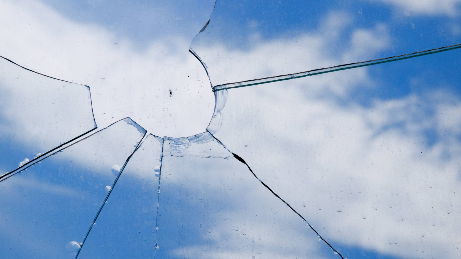 Shattered window pane with sky showing through the broken glass