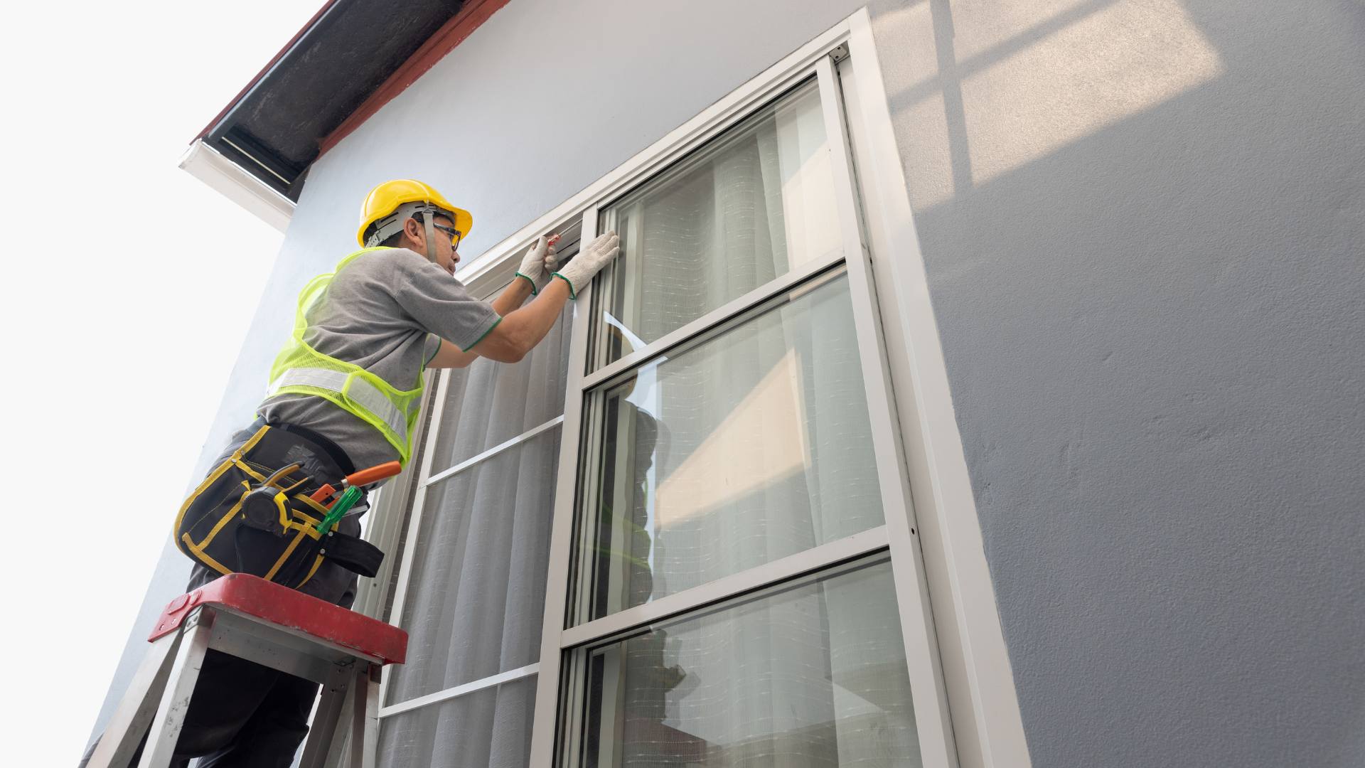 Glass technician installing a window from a ladder
